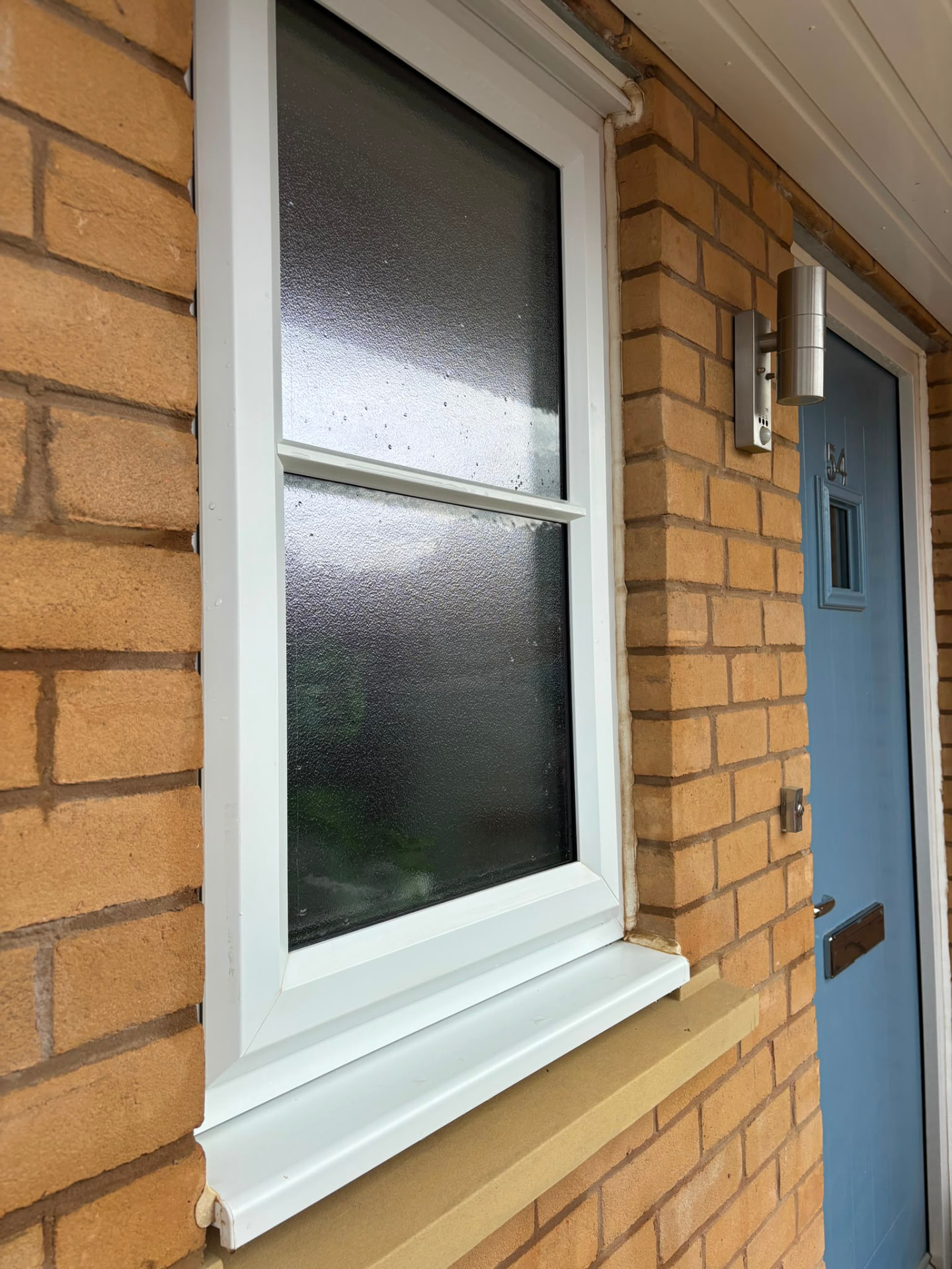 White uPVC frame and sill cleaned beside a blue front door in Northampton