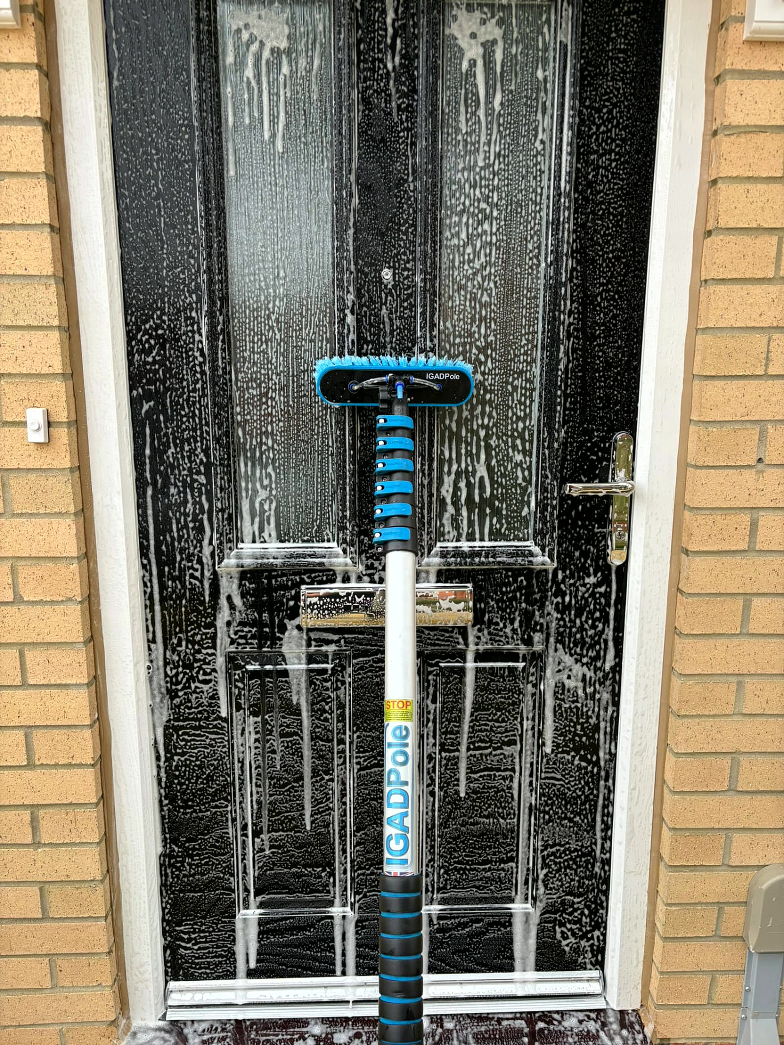 Brush and pure water pole working a soaped composite front door in Northampton