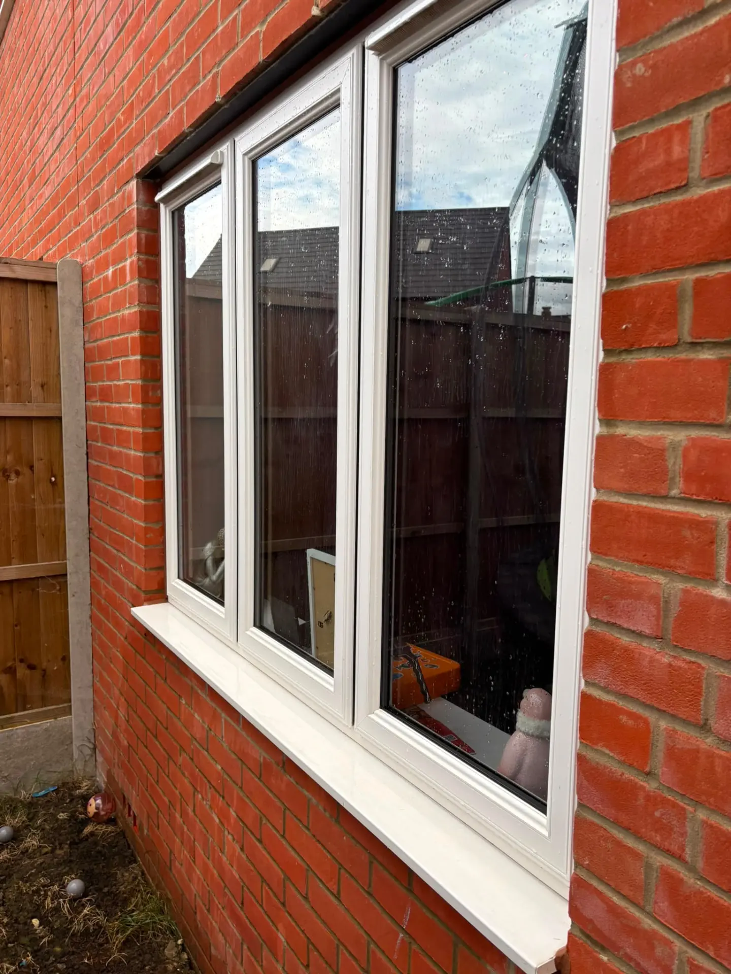 Wide white uPVC window with clean frames and sill on a red brick Northampton home