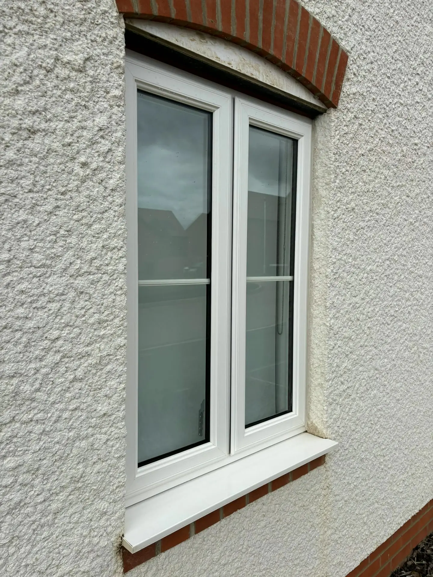 Freshly cleaned white uPVC window and bright sill on a rendered Northampton home