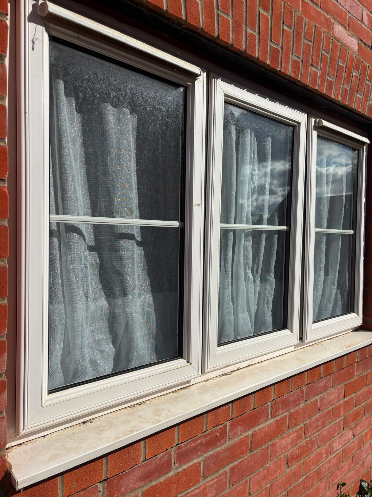 Sunlit white uPVC windows cleaned on a red brick semi in Northampton